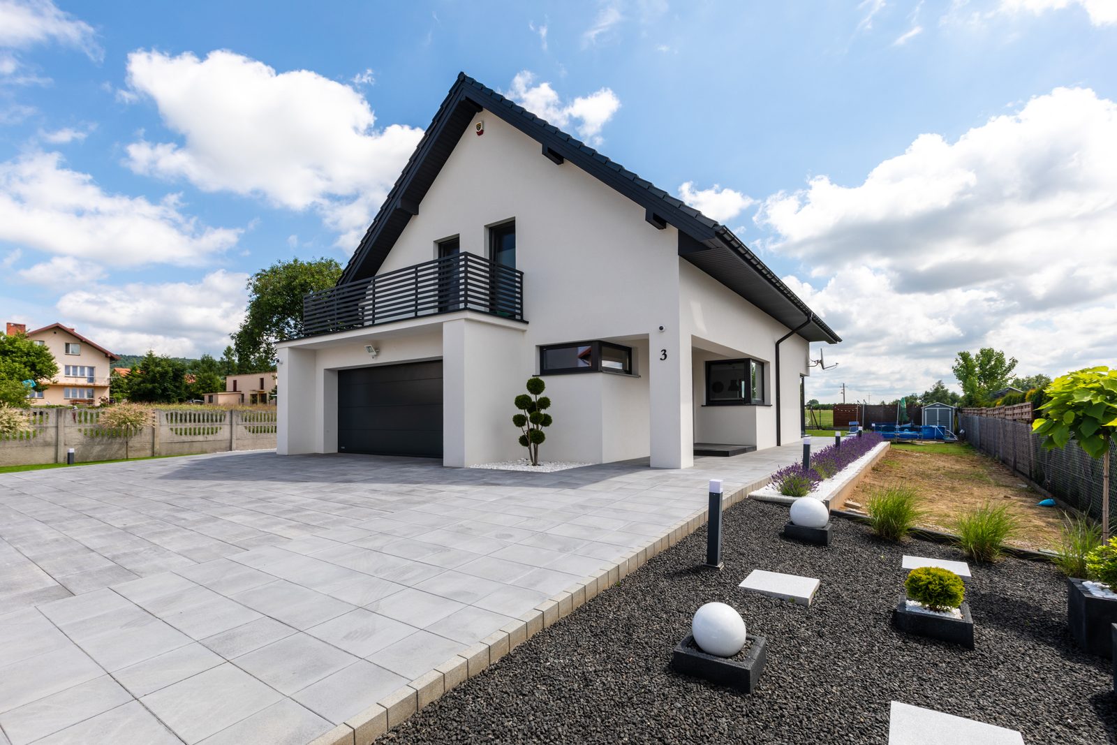 White house with a dark sectional garage door under a balcony